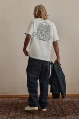 Remera blanca de corte holgado con cuello redondo y estampado de Snoopy con la leyenda "Peanuts Racquet Club" en el pecho.