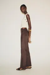 Pantalón marrón acampanado de tiro alto confeccionado en tejido efecto ante con detalle de tachas en la cintura.