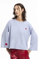 Remera celeste de corte holgado con mangas anchas y estampado de estrella roja en el pecho y logo en la manga.