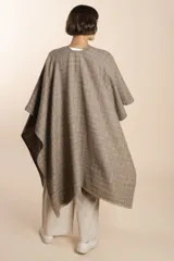 Ruana marrón con diseño a cuadros blancos, terminación envivada y flecos cortos.