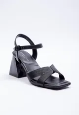 Sandalia alta de símil cuero negra, con taco de 7.5 cm y hebilla en el tobillo, diseño con calados y pespuntes.