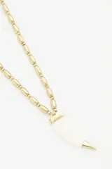 Collar dorado con cuentas cilíndricas y colgante de cuerno blanco con punta dorada.