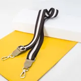 Correa de tela con rayas marrones y blancas, extremos en cuero sintético color beige y ganchos metálicos plateados.
