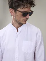 Camisa blanca de lino con cuello mao, manga larga con puños abotonados y bolsillo en el pecho.