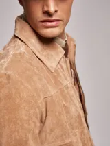 Campera cazadora de gamuza color marrón, con corte clásico y bolsillos frontales.