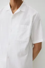 Camisa blanca de manga corta en mezcla de algodón y lino. Modelo con cuello abierto, tapeta lisa y bolsillo superior abierto.