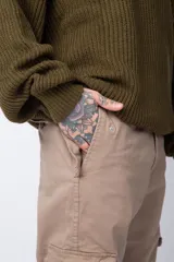 Pantalón cargo color beige con bolsillos laterales con solapa y botón. Corte ajustado.