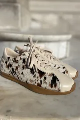 Zapatillas bajas con estampado animal print en blanco, marrón y negro, con puntera y talón en cuero color crema y suela de goma color caramelo.