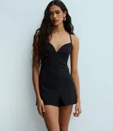 Enterito corto ajustado de sastrería color negro, con escote en V pronunciado y breteles finos. Presenta un detalle con hebilla en la espalda.