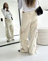 Pantalón cargo negro de denim rígido, corte wide leg, con bolsillos laterales y detalles de tiras con hebillas en los laterales.