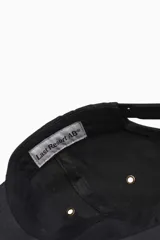 Gorra negra de algodón con visera curva y logo de la marca bordado en blanco en el frente.