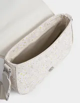 Bandolera con solapa de cuerina estampada con flores. Tiene correa regulable desmontable de algodón y cierre con broche a presión.