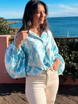 Camisa celeste con estampado abstracto, de corte amplio, cuello camisero y mangas largas abullonadas con puños elásticos.