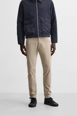 Pantalón chino azul marino, corte skinny fit, confeccionado en tejido de algodón con elasticidad. Cuenta con bolsillos frontales y traseros de vivo. Cierre frontal con cremallera y botón.