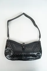 Cartera negra con correa corta para el hombro y tachas plateadas.