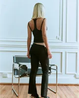 Pantalón negro de gabardina elastizada, corte bootcut, con puntilla en la cintura y lazos laterales.