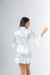 Bata corta color blanco de satén elastizado, con mangas tres cuartos con volados y lazo para atar en la cintura.