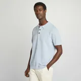 Remera tipo polo celeste de punto con cuello clásico y tres botones marrones.