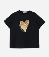 Remera negra de algodón con cuello redondo y manga corta. Presenta un estampado frontal de un corazón dorado de lentejuelas reversibles y texto blanco.