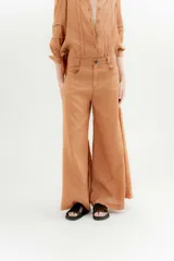 Pantalón de lino color marrón claro, de tiro medio, corte palazzo y bolsillos delanteros.