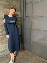 Vestido largo de lana color azul marino, con cuello redondo, mangas largas y parches de cuero en los codos. Presenta aberturas laterales en el ruedo.