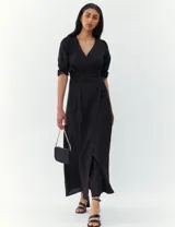 Vestido negro de corte midi, con escote en V cruzado, mangas 3/4 con elástico en los puños y lazo en la cintura.