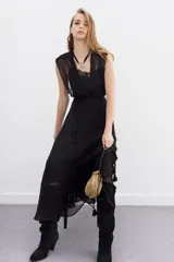 Vestido largo negro de viscosa georgette, con caída fluida y lazo trenzado en la cintura. Presenta doble capa en la parte superior que combina recortes y transparencias.