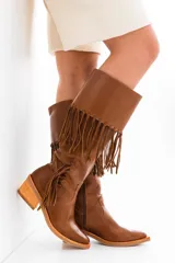 Bota tejana de cuero color marrón, con caña alta con flecos, taco de madera foliado en cuero y cierre lateral.
