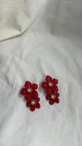 Par de aros colgantes con dos flores rojas y centro dorado.