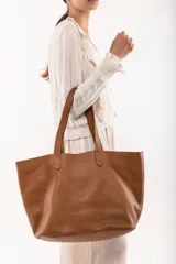 Bolso tote de cuero color tostado, con doble asa de hombro y diseño minimalista. Incluye un bolsillo separador extraíble.