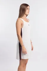 Vestido corto de punto waffle color crudo, con cuello redondo y sisas con ribete marrón. Presenta un logo bordado en el pecho y una banda lateral marrón.