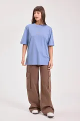 Remera color tostado de algodón con cuello redondo y mangas cortas. Estampado pequeño en el centro del pecho con un sol y texto.