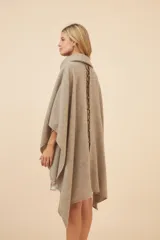 Poncho de lana color marrón con cuello alto, mangas 3/4 y bolsillo lateral con detalle de botones de cuero.