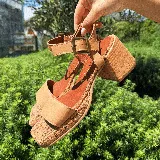 Sandalias de cuero color marrón con plataforma de madera y hebilla dorada.