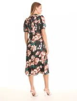 Vestido midi de satén estampado con flores en tonos rosados, blancos y verdes sobre fondo negro. Presenta cuello a la base con frunce, mangas cortas tipo balloon con terminación elastizada, cintura definida y un tajo lateral pronunciado. La espalda cuenta con un lazo para anudar que permite ajustar la caída del cuello. Incluye forro interno a tono.