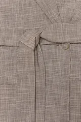 Blazer marrón claro con estampado a cuadros, cuello solapa, manga larga con hombreras, bolsillos delanteros y cierre cruzado con cinturón del mismo tejido.