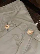 Pantalón color beige con bordado de flores en la pierna y en el tobillo.