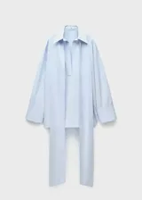Camisa celeste de algodón, corte oversize, con cuello camisero, mangas largas con puños abotonados y cierre de lazo en el cuello.