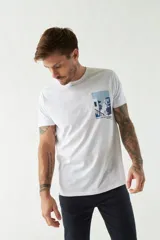 Remera blanca de algodón con estampado de una casa de playa en tonos azules. Corte regular, manga corta y cuello redondo.