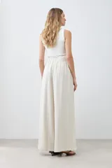 Pantalón palazzo color beige melange de tiro alto con pinzas delanteras y corte amplio.