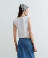 Musculosa corta con estampado de figura mitológica en tonos naranja, blanco y azul sobre fondo negro.