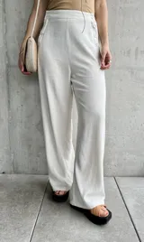 Pantalón de lino color crudo, de corte ancho y largo, con botones decorativos en la cintura.