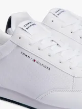 Zapatillas Tommy Hilfiger blancas de estilo running, con suela dentada fina y logo de la marca en el lateral.