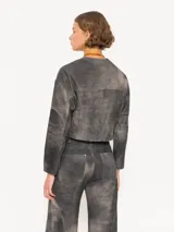 Chaqueta corta de cuero ovino negro con efecto desgastado, cuello mao y cierre frontal con broches metálicos. Presenta bolsillos plaqué en el pecho y corte holgado. Marca JCH.