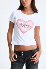 Remera blanca de manga corta con escote redondo y corte cropped. Presenta un estampado frontal de un corazón tridimensional con efecto de rejilla en color rojo y texto cursivo en negro que dice "Too famous for a job".