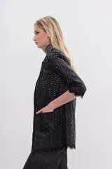 Saco negro de símil cuero con bordado de flores y calado en toda la prenda. Tiene cuello redondo, mangas largas y apertura frontal con broches ocultos.