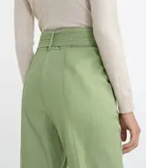 Pantalón zanahoria color verde claro, de tiro alto, con cinturón de la misma tela y hebilla doble.