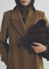 Bolso shopper de gamuza color marrón chocolate, con doble asa corta y asa de hombro. Tiene cierre de cremallera y lazo ajustable, forro interior de algodón y un bolsillo interno con cremallera.