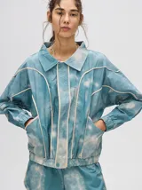 Campera rompevientos estilo biker con capucha desmontable, color celeste con estampado de nubes blancas y detalles en blanco.