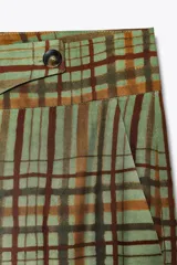 Pantalón de tiro medio con estampado de cuadros color verde y marrón, confeccionado en hilatura de viscosa. Tiene bolsillos delanteros, corte crop y bajo acampanado. Cierre frontal con cremallera y botón.